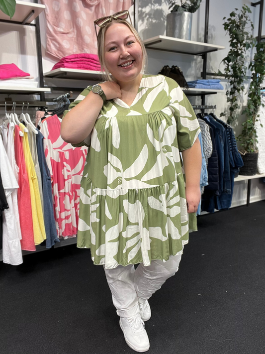 Plus size tunika i den gode a-facon, som man aldrig går fejl af. Den er med smart print, og fås i flere forskellige farver. Den er med korte ærmer og overskæring på brystet.
