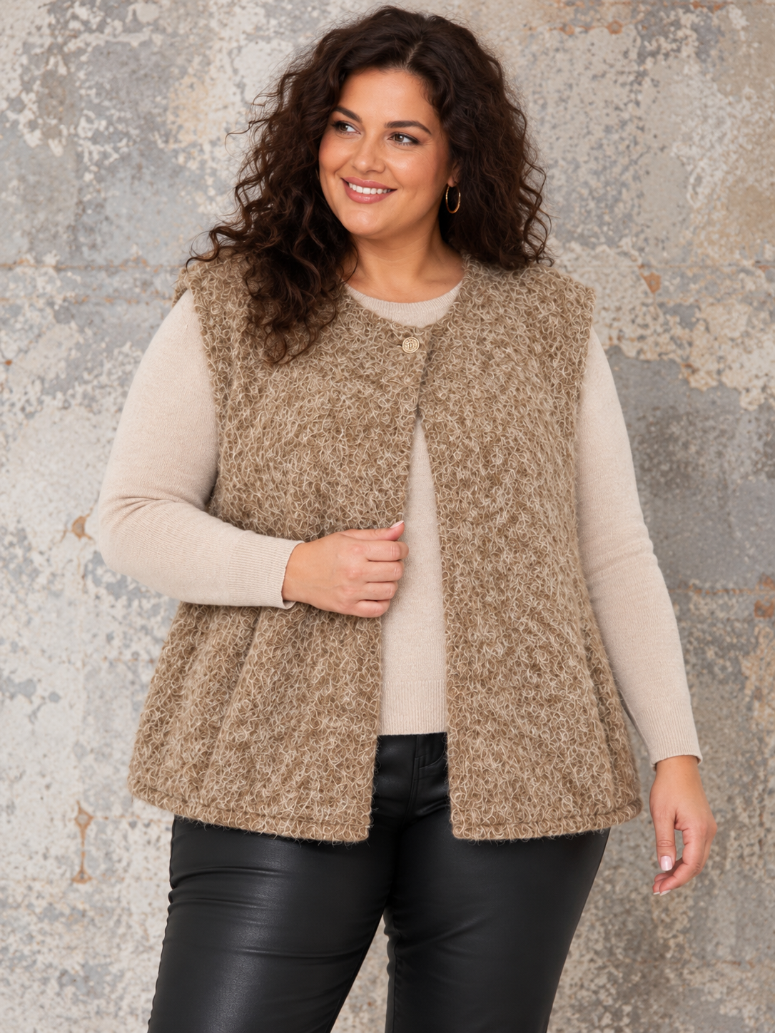 Boucle vest med god pasform og facon til plus size kvinden. Den er perfekt under en strik da ærmegabet har en god størrelse. Den er rund i halsen og spændes med en knap foroven. 

Billedet er genereret vha. AI-teknologi.