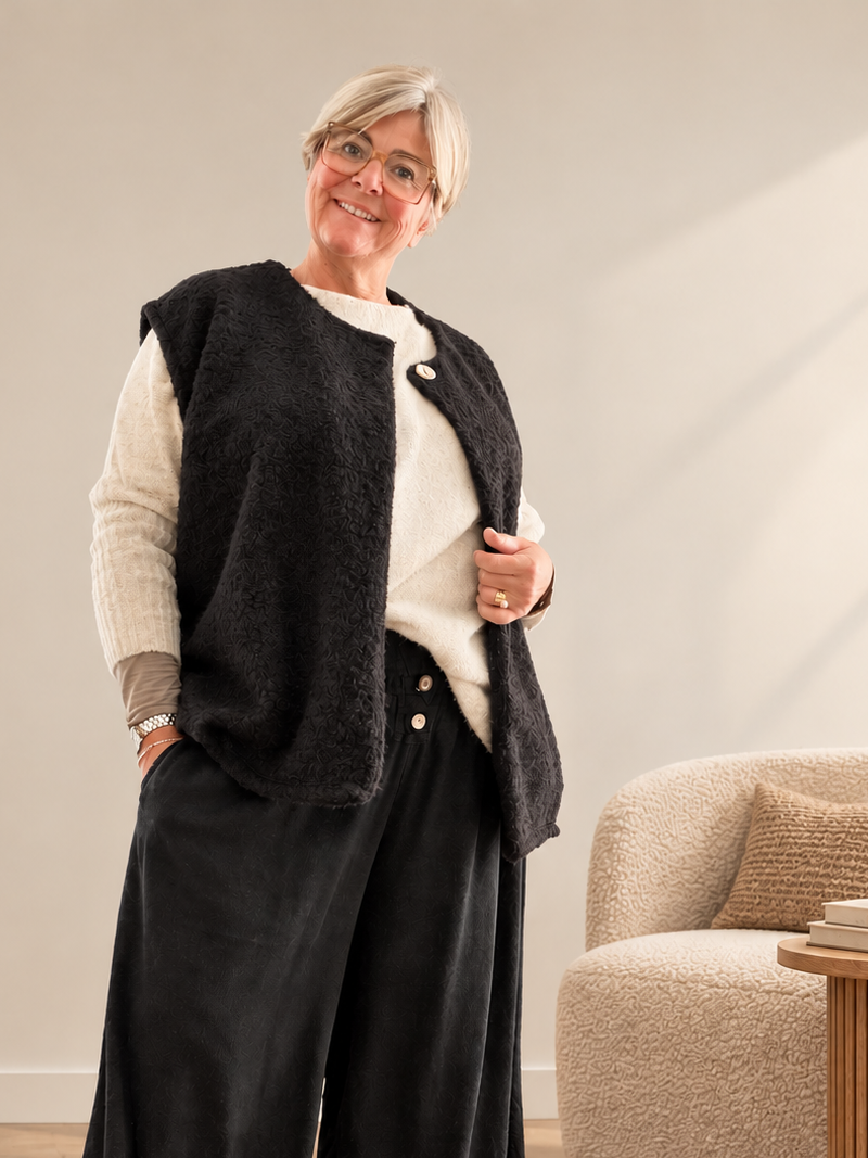 Boucle vest med god pasform og facon til plus size kvinden. Den er perfekt under en strik da ærmegabet har en god størrelse. Den er rund i halsen og spændes med en knap foroven. 

Billedet er genereret vha. AI-teknologi.