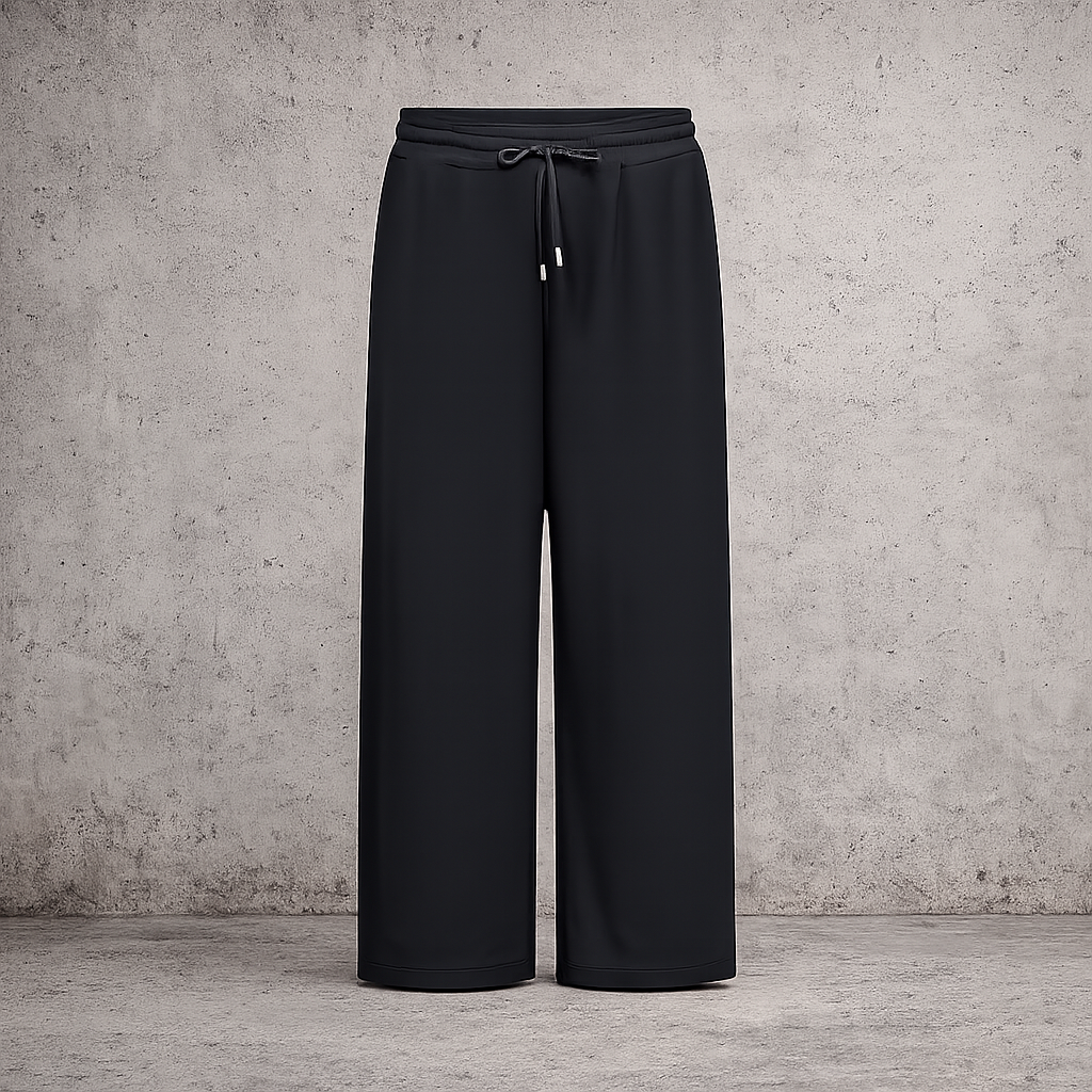 **Alt-tekst – Sabina 2 plussize buks (AI-genereret billede):**

AI-genereret billede af plus-size model i størrelse 50 iført sorte Sabina 2 bukser fra Wasabi. Bukserne har elastisk talje med bindebånd, lige brede ben og praktiske sidelommer. Modellen har bukserne stylet med en sort sweatshirt over en hvid skjorte og hvide sneakers. Billedet er taget udendørs foran en moderne bygning og viser buksernes afslappede pasform og komfortable look.
