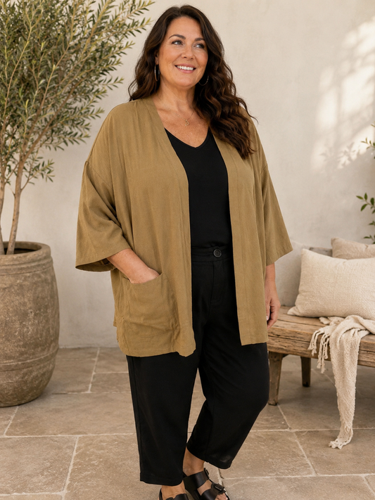 Sanne plus size kimono med åben front, store lommer og bindebælte. Den løse pasform gør kimonoen behagelig og nem at style over en T-shirt, top eller kjole. Perfekt til kvinder i plus size, der ønsker et afslappet og moderne look. Fås hos Sigensgaard.dk. billed er Ai generet.