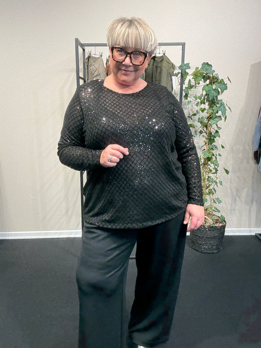 Plus size bluse i et flot paillet mønster. Den er med lange ærmer, rund hals og har en lille lykke i ryggen. Perfekt til årstidens fester. 