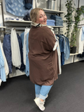 Sia 5 er en lang plus size skjorte, fra mærket Wasabi, modellen bruger den her som en åben jakke, men den kan også lukkes helt da den er gennemknappet. 