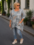 AI-genereret billede af Sille plussize bomuldstunika i let vævet bomuld med grafisk print, rund hals og lommer. Tunikaen vises på en plus-size model og fås i flere farver.