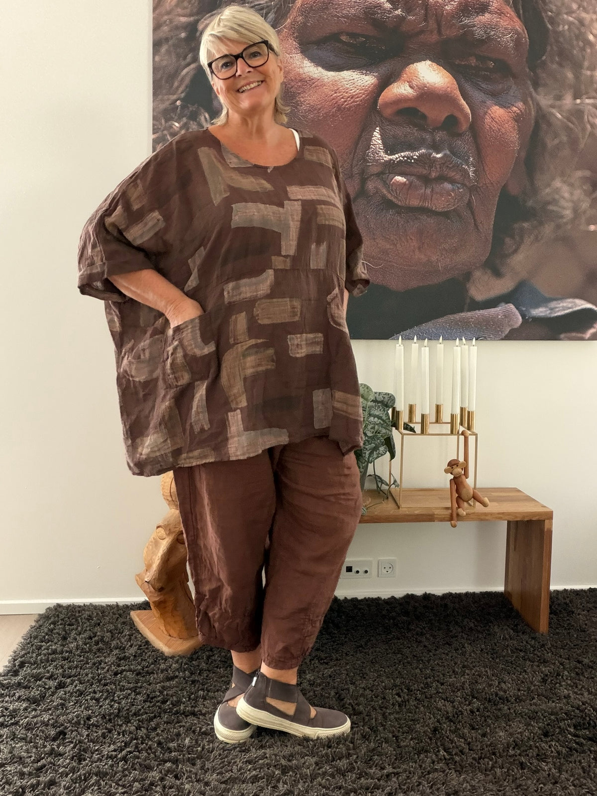 AI-genereret billede af Sille plussize bomuldstunika i let vævet bomuld med grafisk print, rund hals og lommer. Tunikaen vises på en plus-size model og fås i flere farver.