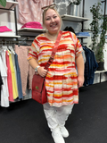Plus size tunika i smukke brændte farver. Den er med korte ærmer og overskæring på bryst, og så går den ud i en flatterende a-facon, som er klædelig til de fleste plus piger. 