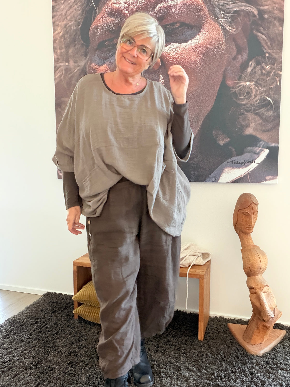 **Alt-tekst – Susanne plussize bomuldstunika (AI-genereret billede):**

AI-genereret billede af en smilende plus-size model iført Susanne bomuldstunika i mørk brun. Tunikaen har en løs, oversize pasform med rund hals, korte brede ærmer og store påsyede lommer foran. Den er stylet med rustfarvede bukser og komfortable sko i et råt industrielt miljø, som fremhæver tunikaens afslappede og moderne udtryk. Ideel til kvinder, der ønsker komfort, bevægelsesfrihed og et stilfuldt hverdagslook.