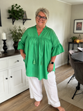 Den smukke plus size tunika ved navn Thea, her i grøn. Jeg har sat den til Mimi jeansen, det er den med stræk, lommer bindebånd og god pasform. 

Billedet er genereret vha. AI-teknologi for at vise tunikaen på en person. 