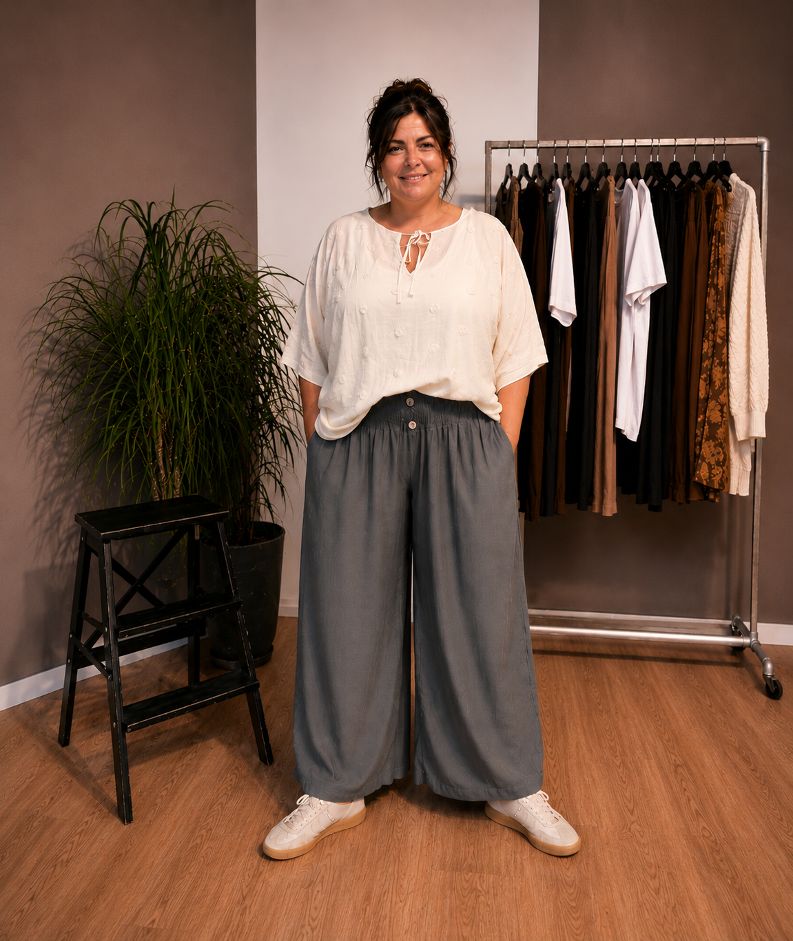 "Model i Tora viddebuks med bred smock-elastik i taljen, dekorative knapper og vide ben. Buksen vises i Grå sammen med en løs beige bluse. Modellen er str. 46/48 og 168 cm høj." Billed er ændret i Ai