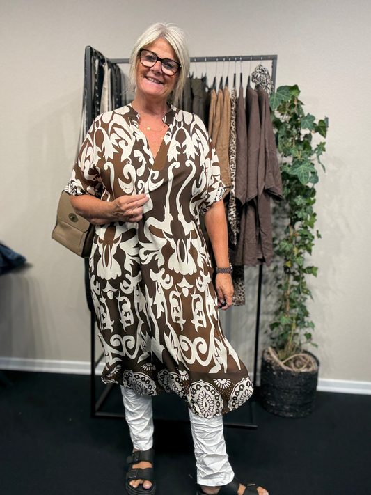 Smart plus size kjole som går lige op og ned, har runding i bunden, hvor den yderligere går en smule op i siderne. Derudover har den V-hals og er med kort ærmer.
