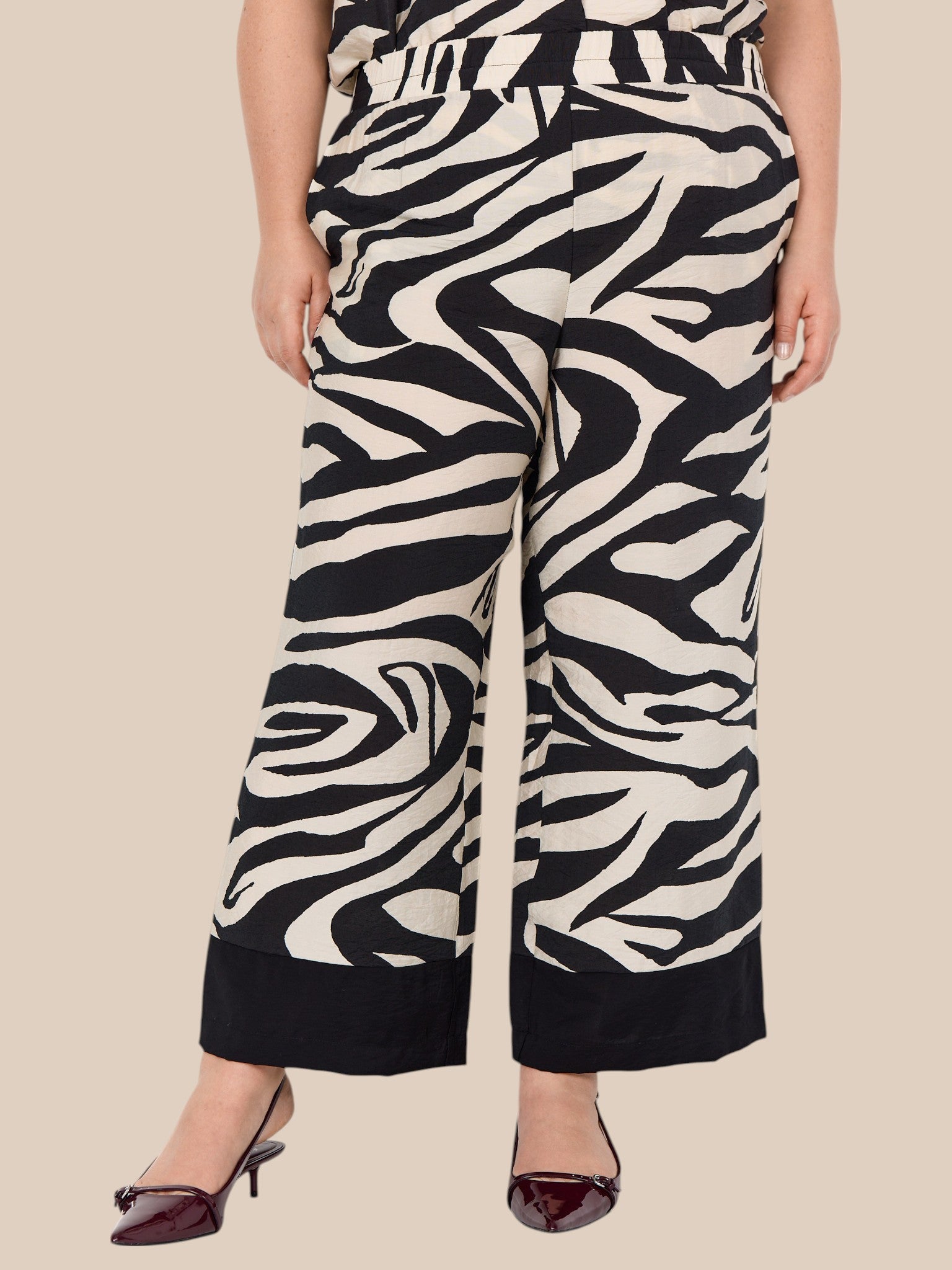 Smart plus size buks i zebra print med brede ben, lommer, elastik i livet og et bredt ensfarvet stykke ved buksens afslutning.