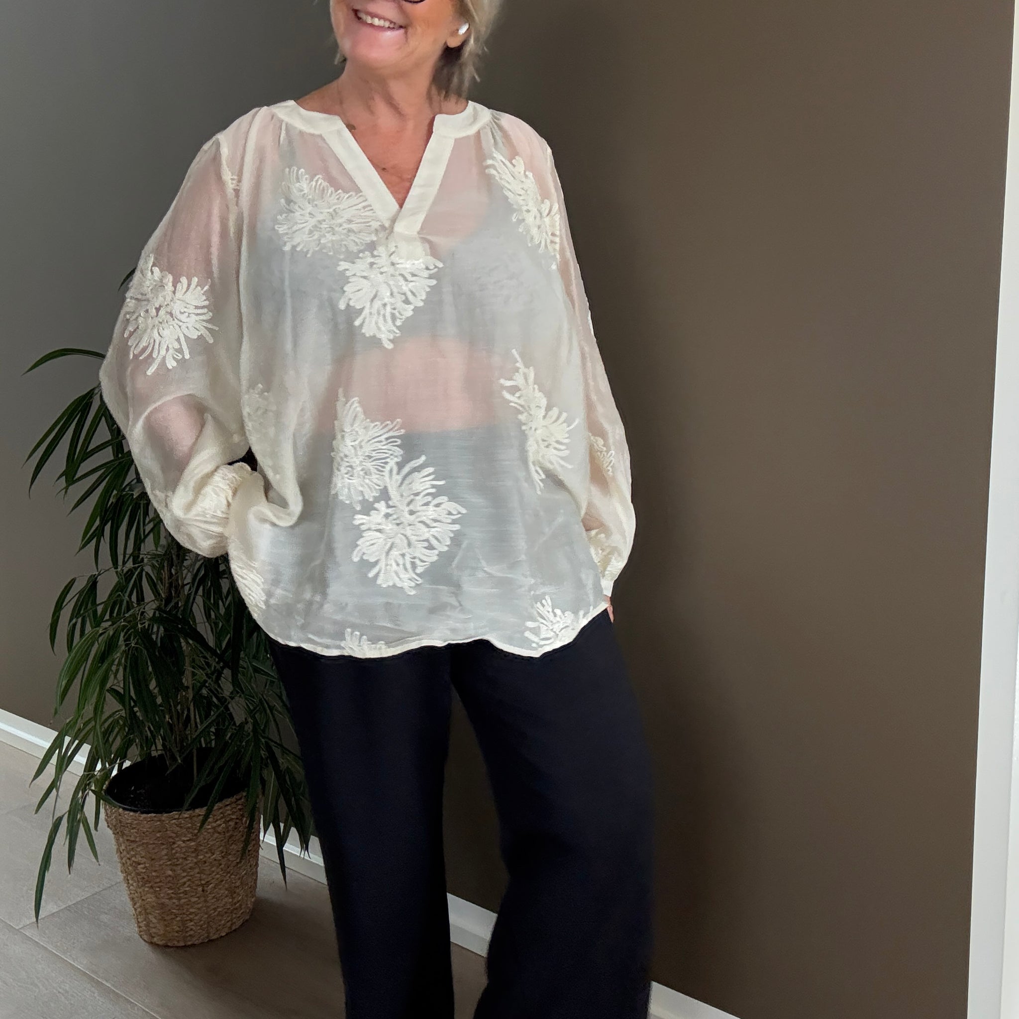 Feminin plus size bluse i en smuk fløde-farve. Den er med broderede blomster, som gør den lidt pyntet.