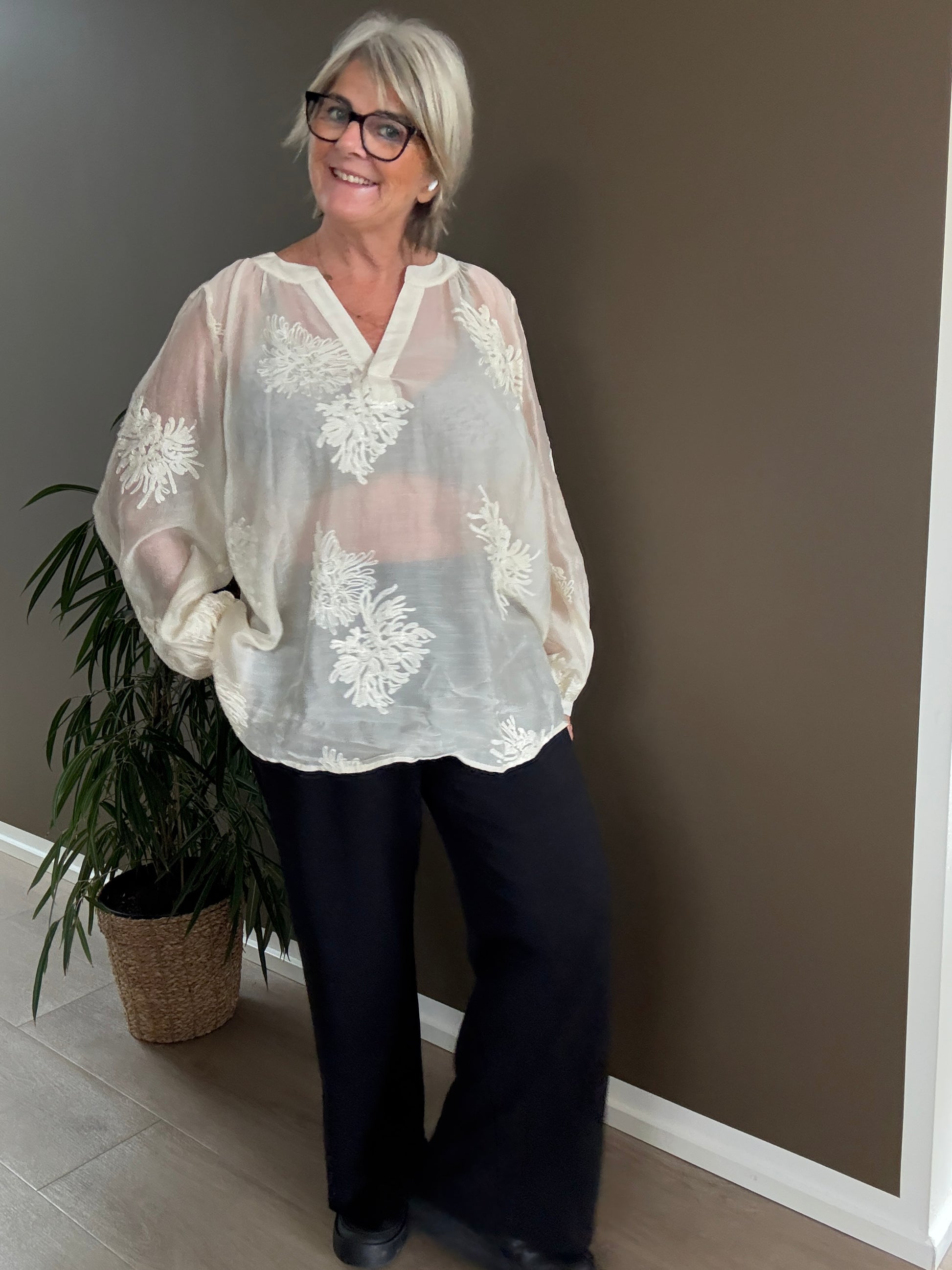 Feminin plus size bluse i en smuk fløde-farve. Den er med broderede blomster, som gør den lidt pyntet.