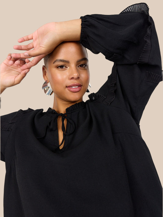 Smuk plus size bluse fra Wasabi. Den er med flæse-detaljer på ærmerne, som gør den pyntet, og perfekt til både hverdag og festlige lejligheder.