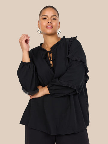 Smuk plus size bluse fra Wasabi. Den er med flæse-detaljer på ærmerne, som gør den pyntet, og perfekt til både hverdag og festlige lejligheder.