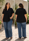 Plus size model bærer sort kortærmet bluse med V-udskæring, fine hulmønsterdetaljer og let løs pasform, vist både forfra og bagfra i solrigt udendørsmiljø.

Billedet er generet vha. AI