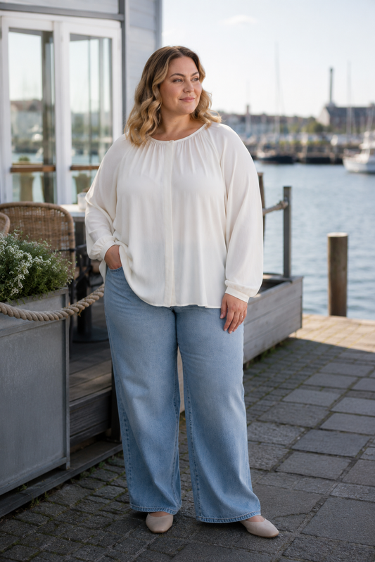 Sød bluse med langt ærme med balloneffekt. Den falder pænt hvilket skyldes den lækre viskose-kvalitet. Den er gennemknappet og med rund hals. 

Billedet er genereret vha. AI. 