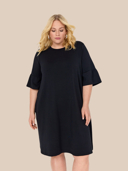 Smart plus size kjole med korte flæseærmer, som går ud og laver trompet-effekt. Kjolen er knælang, og kan benyttes sammen med rigtig mange ting. Kan nemt dresses op. 