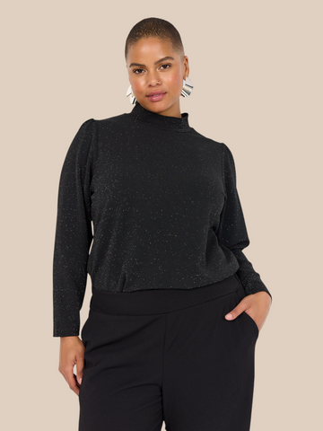 Smuk plus size bluse med glimmer. Den passer til bukserne af samme navn. Den er med lange ærmer og turtleneck. 
