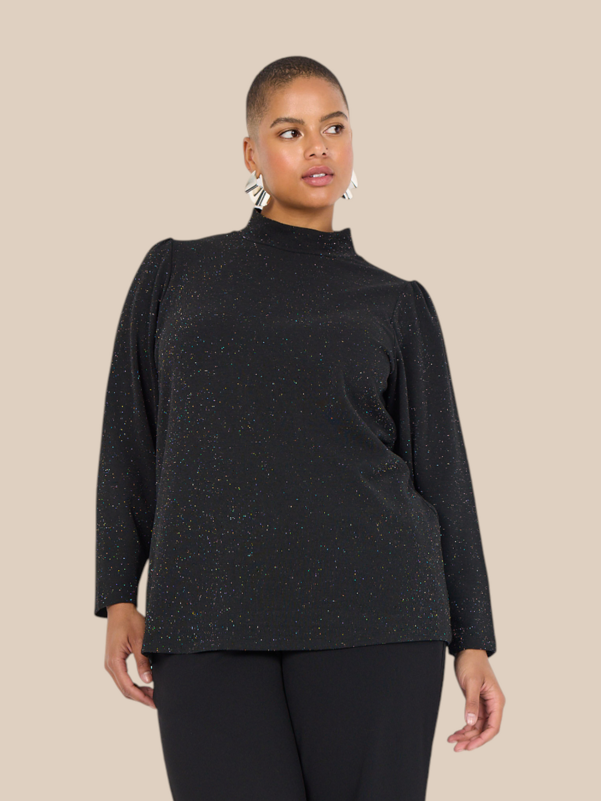 Smuk plus size bluse med glimmer. Den passer til bukserne af samme navn. Den er med lange ærmer og turtleneck. 