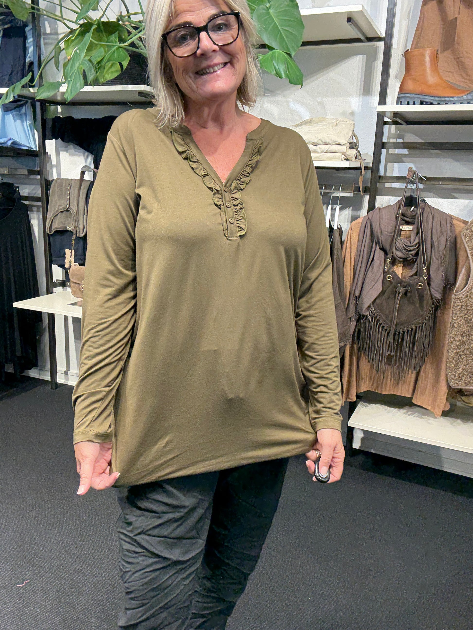 Flot plus size bluse med v-hals og stolpelukning hvor der er påsat flæsekant, som giver et feminint udtryk.kvalitet er jersey så den er blød og lækker
