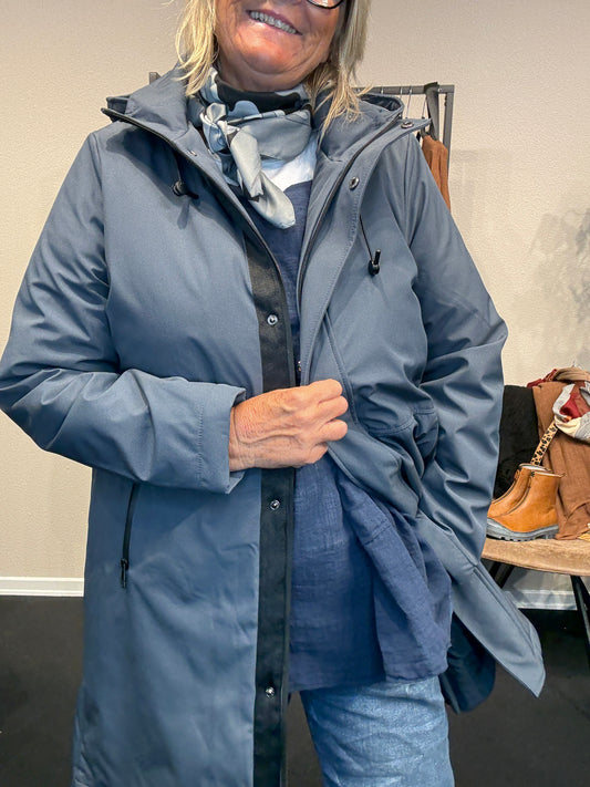 Smart og funktionel plus size jakke efterårs/vinter jakke hvor der er mulighed for at knappe en smule op i siden. Den er med lange ærmer, hætte og så har den lynlås lukning hele vejen ned, samt lommer med lynlås. Rigtig god længde som går til lige under knæet.