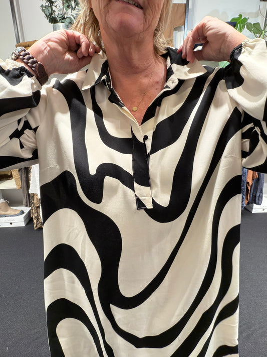 Anderledes tunika til plus size kvinden. Den er med stolpelukning, lange ærmer og en klassisk skjortekrave. 