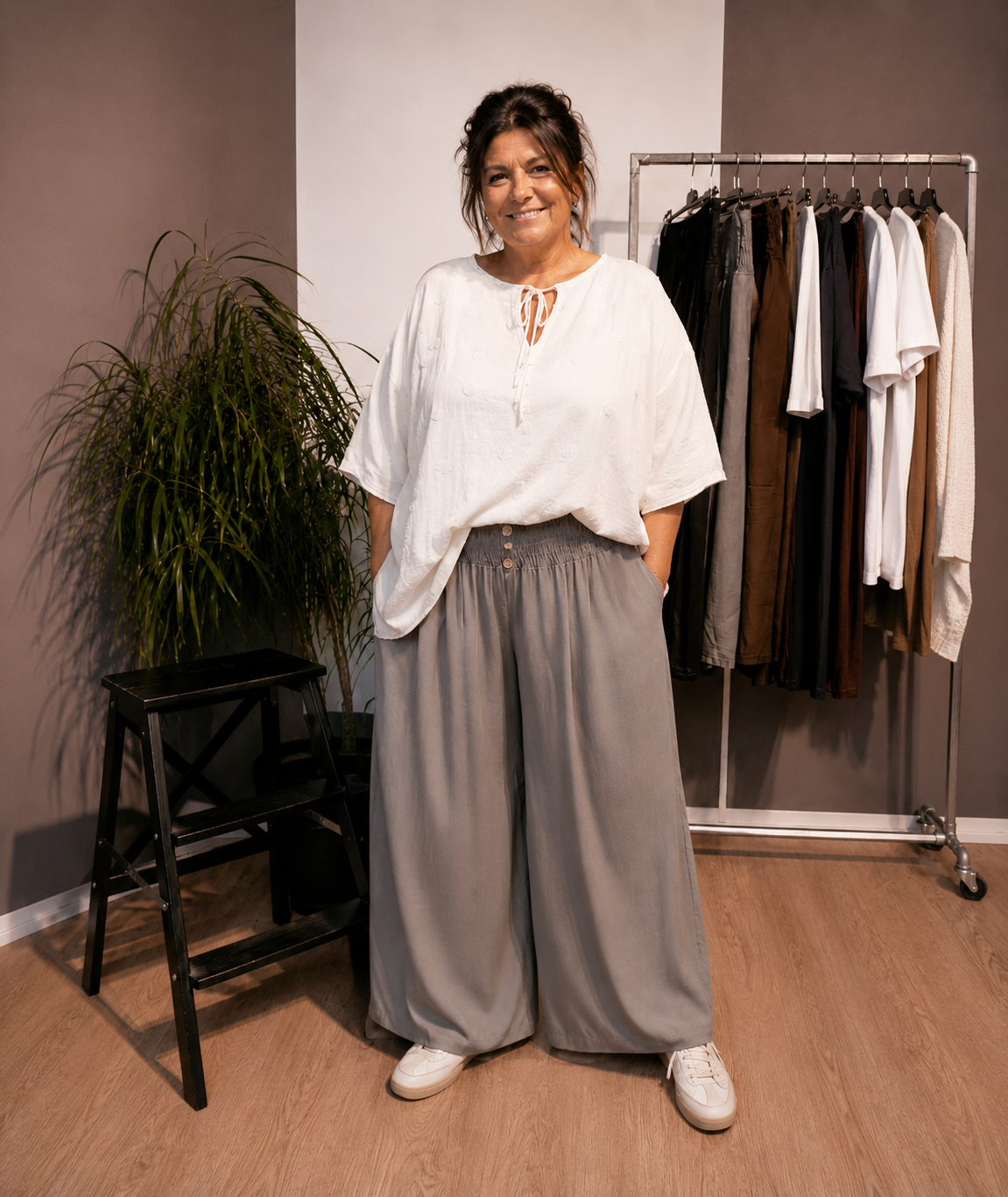 "Model i Tora viddebuks med bred smock-elastik i taljen, dekorative knapper og vide ben. Buksen vises i Taupe  sammen med en løs hvid bluse. Modellen er str. 46/48 og 168 cm høj." Blled er ai generet