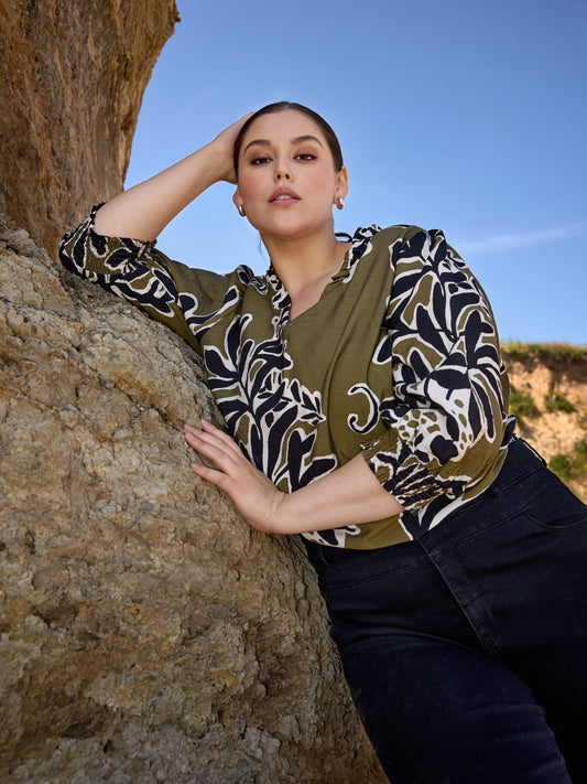 Mønstret plus size bluse med v-hals og flot rynke-detalje ved halsen. Den er med 3/4 ærmer, hvor der er smock afslutning, som gør at ærmet kan placeres hvor det lyster. Det giver også mulighed for at skabe ballon-effekt.