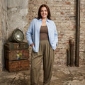 Mary 8 Plus Size skjorte i lyseblå med klassisk krave og lange ærmer. Skjorten bæres åben over en brun top og har en løs, komfortabel pasform. Vist på model i størrelse 